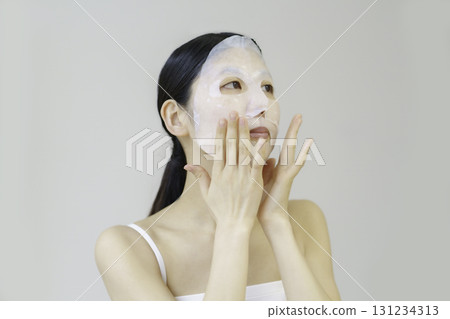 Young woman applying sheet mask Young woman applying sheet mask 131234313