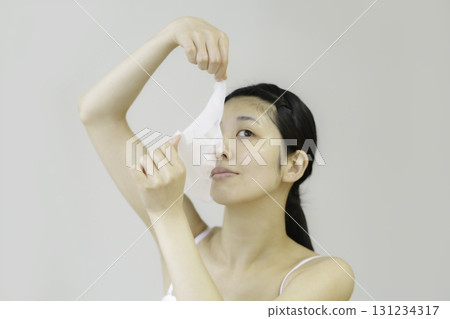 Young woman applying sheet mask Young woman applying sheet mask 131234317
