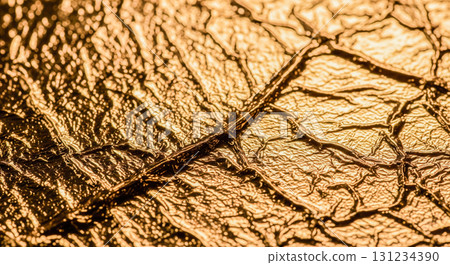 Golden foil macro detail showing rich and expensive surface perfect for festive invitation card or glamorous fashion and jewelry themes 131234390