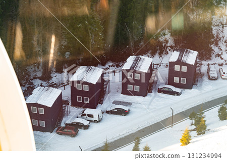 Snow-covered cabins nestled in a tranquil winter landscape at dawn Snow-covered cabins nestled in a tranquil winter landscape at dawn 131234994