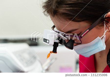 Skilled professional engaged in detailed examination in a sterile environment, showcasing dedication and focus in precision work with advanced tools 131235006