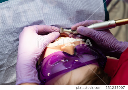 Dentist performing dental procedure with precision on a patient under bright clinical lights in a modern dental office environment, showcasing advanced techniques and tools for oral health Dentist performing dental procedure with precision on a patient under bright clinical lights in a modern dental office environment, showcasing advanced techniques and tools for oral health 131235007