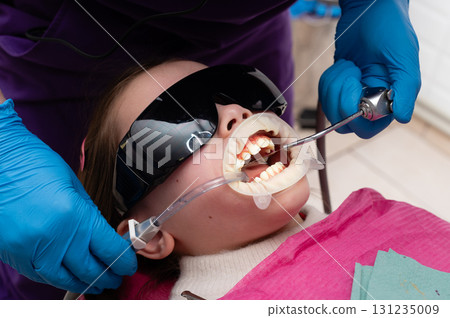 Dental care experience for a young patient in a clinic during a routine checkup with advanced equipment and attentive professionals ensuring comfort Dental care experience for a young patient in a clinic during a routine checkup with advanced equipment and attentive professionals ensuring comfort 131235009