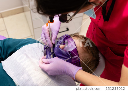 Young patient receiving dental care while wearing protective eyewear in a bright clinic setting during a routine check-up Young patient receiving dental care while wearing protective eyewear in a bright clinic setting during a routine check-up 131235012