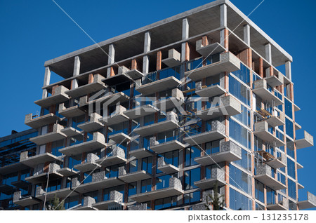 Modern architectural marvel featuring a multi-level building against a clear blue sky in a bustling urban setting during the bright sunlight of midday 131235178