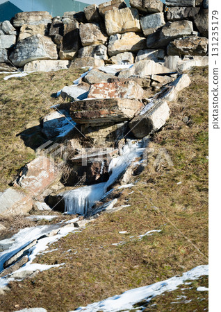 Boulders and snow melt create a natural waterway in a serene landscape during early spring in a mountainous region Boulders and snow melt create a natural waterway in a serene landscape during early spring in a mountainous region 131235179