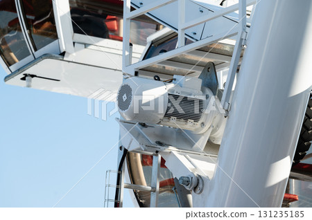 Impressive engineering of a modern ferris wheel against a clear blue sky showcasing intricate designs and fine details of the cabin mechanism Impressive engineering of a modern ferris wheel against a clear blue sky showcasing intricate designs and fine details of the cabin mechanism 131235185