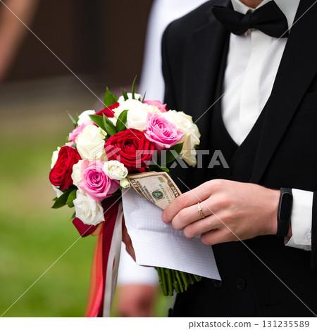 Groom holding wedding bouquet with hidden money. A unique and memorable wedding detail. Groom holding wedding bouquet with hidden money. A unique and memorable wedding detail. 131235589