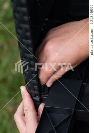 Assembling outdoor furniture. Hands connect woven plastic pieces. Assembling outdoor furniture. Hands connect woven plastic pieces. 131236095