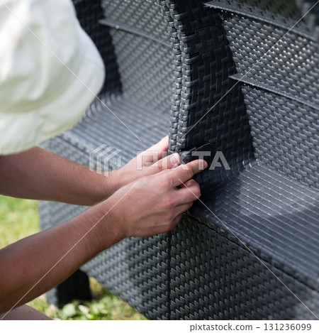 Assembling outdoor wicker furniture. Hands connect pieces. Assembling outdoor wicker furniture. Hands connect pieces. 131236099