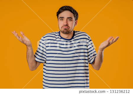 Young man shrugs shoulders showing uncertainty, confusion, dilemma, hesitation 131236212