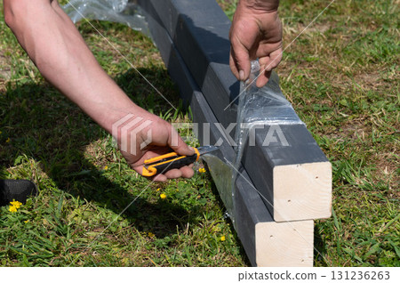 A person uses a stationery knife to cut the film on the boards. 131236263