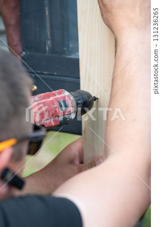 Screwing the board with a screwdriver, installing a wooden gazebo. Screwing the board with a screwdriver, installing a wooden gazebo. 131236265