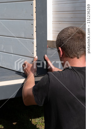 Installing a wall of wooden planks painted white in a gazebo. 131236269