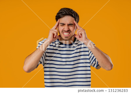 20s aged man having headache, touching temples, Suffering on yellow background. 20s aged man having headache, touching temples, Suffering on yellow background. 131236283