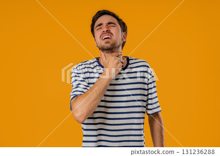 Young Man Has Sore. Sick Guy With Swollen Throat On Yellow Studio. Angina, pain Young Man Has Sore. Sick Guy With Swollen Throat On Yellow Studio. Angina, pain 131236288