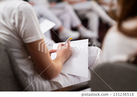 Close up of a student holding a pen and writing notes in a notebook during a professional training and education session in a wellness and therapy course 131236518