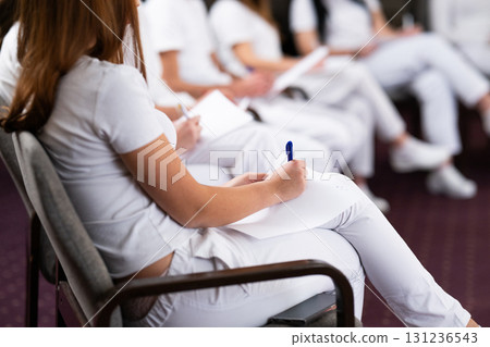 Close up of a student holding a pen and writing notes in a notebook during a professional training and education session in a wellness and therapy course 131236543