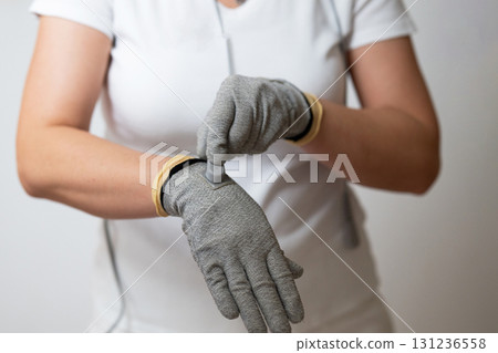 Close up shot of a therapist adjusting special conductive electrotherapy gloves before a physiotherapy session. Concept of modern rehabilitation, healthcare technology, pain management, and Close up shot of a therapist adjusting special conductive electrotherapy gloves before a physiotherapy session. Concept of modern rehabilitation, healthcare technology, pain management, and 131236558