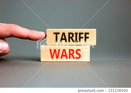 Trade tariff wars symbol. Concept word Tariff wars on beautiful wooden blocks. Beautiful grey paper background. Businessman's hand. Business trade tariff wars concept. Copy space. Trade tariff wars symbol. Concept word Tariff wars on beautiful wooden blocks. Beautiful grey paper background. Businessman's hand. Business trade tariff wars concept. Copy space. 131236593