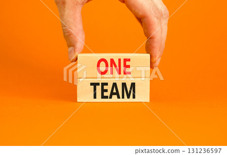 One team symbol. Concept word One team on beautiful wooden blocks. Beautiful orange paper background. Businessman's hand. Business one team concept. Copy space. One team symbol. Concept word One team on beautiful wooden blocks. Beautiful orange paper background. Businessman's hand. Business one team concept. Copy space. 131236597