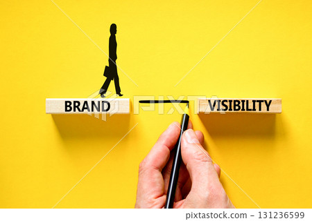 Brand visibility symbol. Concept words Brand visibility on wooden blocks. Beautiful yellow table yellow background. Businessman hand. Business branding and brand visibility concept. Copy space. 131236599