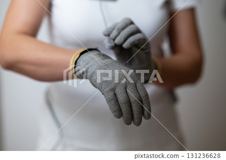 Close up shot of a therapist adjusting special conductive electrotherapy gloves before a physiotherapy session. Concept of modern rehabilitation, healthcare technology, pain management, and Close up shot of a therapist adjusting special conductive electrotherapy gloves before a physiotherapy session. Concept of modern rehabilitation, healthcare technology, pain management, and 131236628