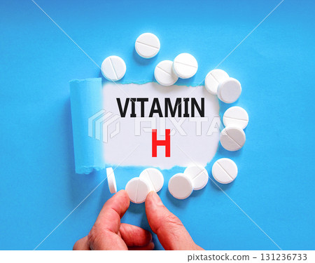Vitamin H symbol. Concept words Vitamin H on beautiful white paper. White pills tablets. Doctor's hand. Beautiful blue background. Medical healthy lifestyle Vitamin H concept. 131236733