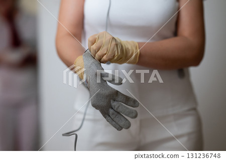 Close up shot of a therapist adjusting special conductive electrotherapy gloves before a physiotherapy session. Concept of modern rehabilitation, healthcare technology, pain management, and Close up shot of a therapist adjusting special conductive electrotherapy gloves before a physiotherapy session. Concept of modern rehabilitation, healthcare technology, pain management, and 131236748