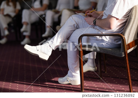 Close up of a student holding a pen and writing notes in a notebook during a professional training and education session in a wellness and therapy course 131236892