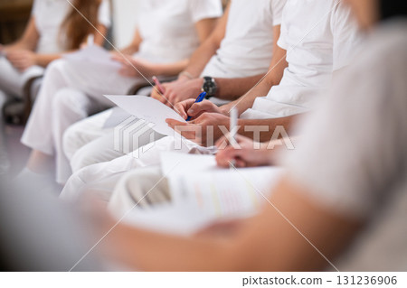 Close up of a student holding a pen and writing notes in a notebook during a professional training and education session in a wellness and therapy course Close up of a student holding a pen and writing notes in a notebook during a professional training and education session in a wellness and therapy course 131236906