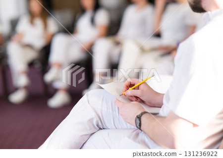 Close up of a student holding a pen and writing notes in a notebook during a professional training and education session in a wellness and therapy course Close up of a student holding a pen and writing notes in a notebook during a professional training and education session in a wellness and therapy course 131236922