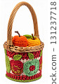 Handmade Woven Basket Filled with Knitted Apples and Green Leaves on White Backdrop 131237718