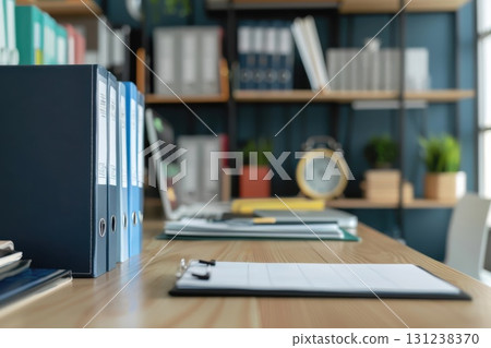 Contemporary office scene showing work desk and shelf stacked with binders, files, and notebooks in background 131238370