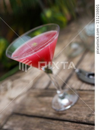 red cocktail with ice in glass with stem on wooden surface red cocktail with ice in glass with stem on wooden surface 131238601