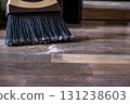 Close-up of a broom sweeping dust and dirt on a wooden floor 131238603