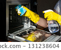 A person wearing yellow rubber gloves is cleaning an oven 131238604