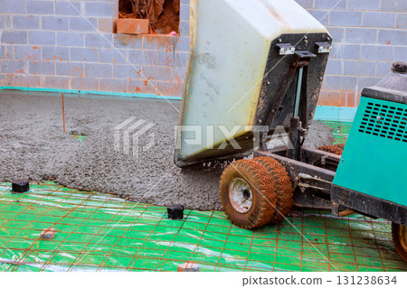 Concrete mixer deposits fresh cement onto construction site wheeled concrete wheelbarrow usage preparing for building. Concrete mixer deposits fresh cement onto construction site wheeled concrete wheelbarrow usage preparing for building. 131238634