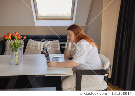 Bored woman working on laptop at home office 131238914