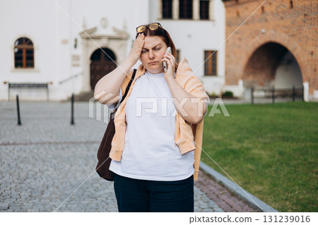 Redhead 30s woman with headache calling phone outdoor in street. 131239016