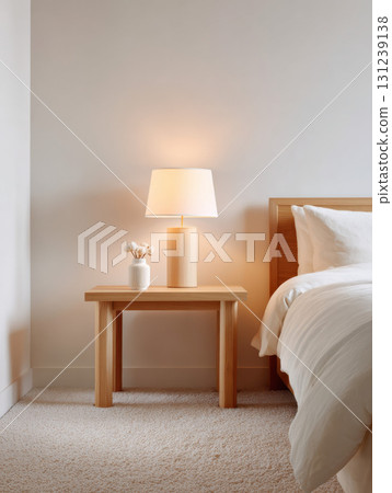 Cozy and tranquil bedroom interior with minimalist home decor. warm lamp on wooden nightstand creates peaceful mood next to simple bed furniture 131239138