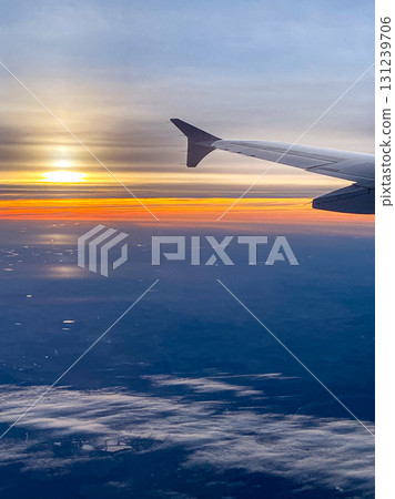 A picture from an airplane of a sunset. View from the window with the wing visible 131239706