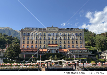 Beautiful building of the Grand Hotel Tremezzo seen from the lake side (Lake Como) in Italy (people's faces are unrecognizable) Beautiful building of the Grand Hotel Tremezzo seen from the lake side (Lake Como) in Italy (people's faces are unrecognizable) 131239767