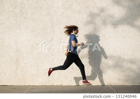 Side view of male athlete running against wall Side view of male athlete running against wall 131240046