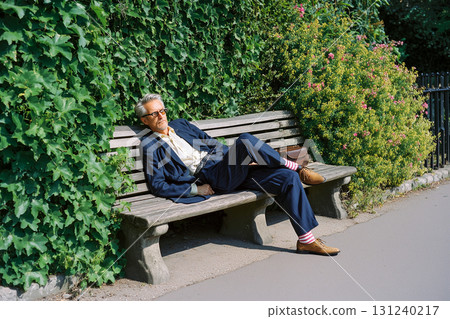 A man is sitting on a bench in a park 131240217