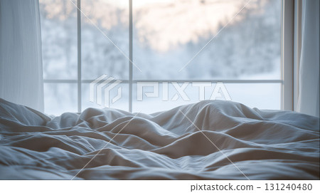 Messy cozy bed with rumpled sheets near large window overlooking peaceful snowy winter landscape Messy cozy bed with rumpled sheets near large window overlooking peaceful snowy winter landscape 131240480