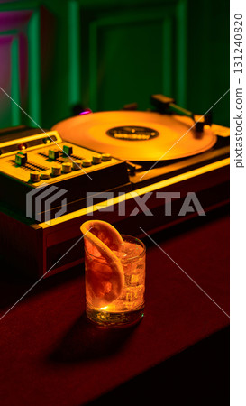 Classic cocktail glass with cherry garnish near record player under green neon glow Classic cocktail glass with cherry garnish near record player under green neon glow 131240820