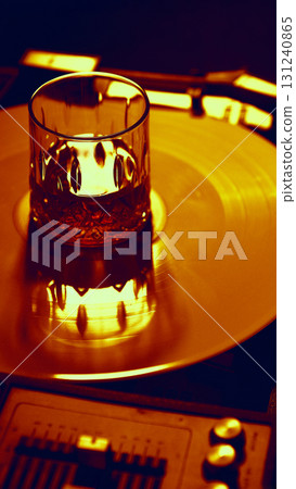 Whiskey glass glowing on golden vinyl with warm reflections 131240865