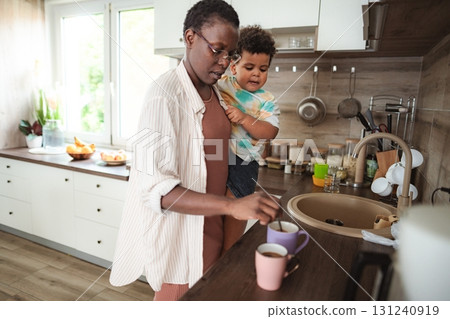 Black mother holding son preparing coffee in kitchen 131240919