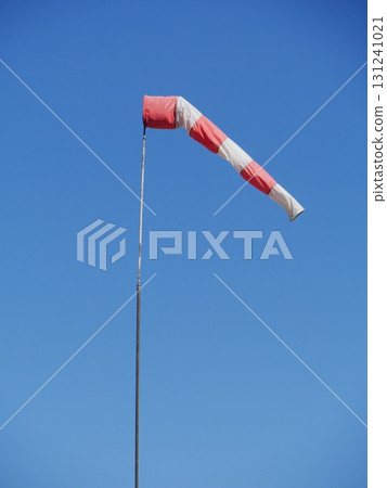Red and white striped kite is flying in the sky Red and white striped kite is flying in the sky 131241021
